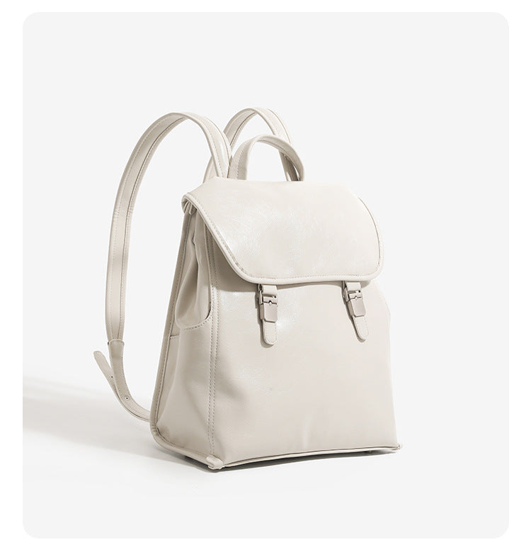 Structured glossy leather-look flap backpack handbag with dual buckle closures, top handle, and silver-tone hardware, detail