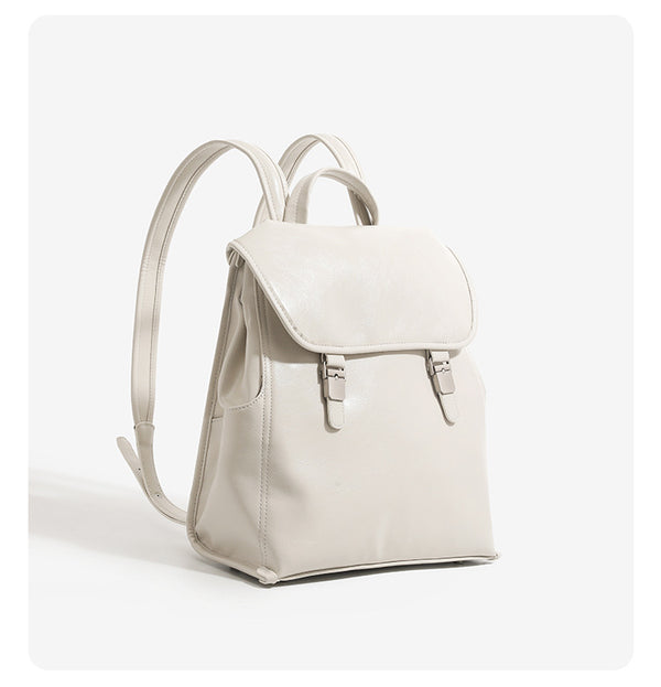 Structured glossy leather-look flap backpack handbag with dual buckle closures, top handle, and silver-tone hardware, detail