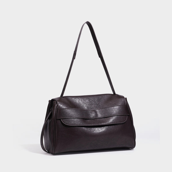 Strukturierte rechteckige Schultertasche in Dunkelbraun mit Überschlag aus Lederoptik, mehrlagigem Detail auf der Vorderseite und langem verstellbarem Riemen, Detailansicht