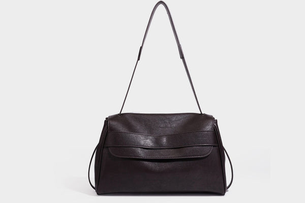 Strukturierte rechteckige dunkelbraune Schultertasche in Lederoptik mit Klappe, mehrlagigem Detail auf der Vorderseite und langem verstellbarem Riemen, Detailansicht