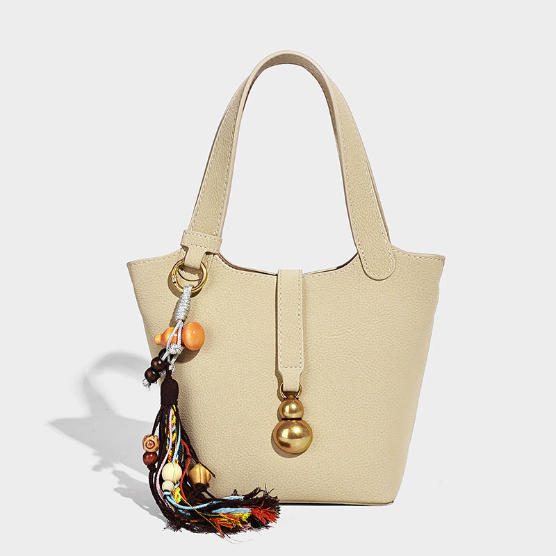 Kleine Beuteltasche mit genarbter, matter Oberfläche, antikgoldfarbenen Ringbeschlägen, Perlen- und Quastenanhänger, kurzen Henkeln und