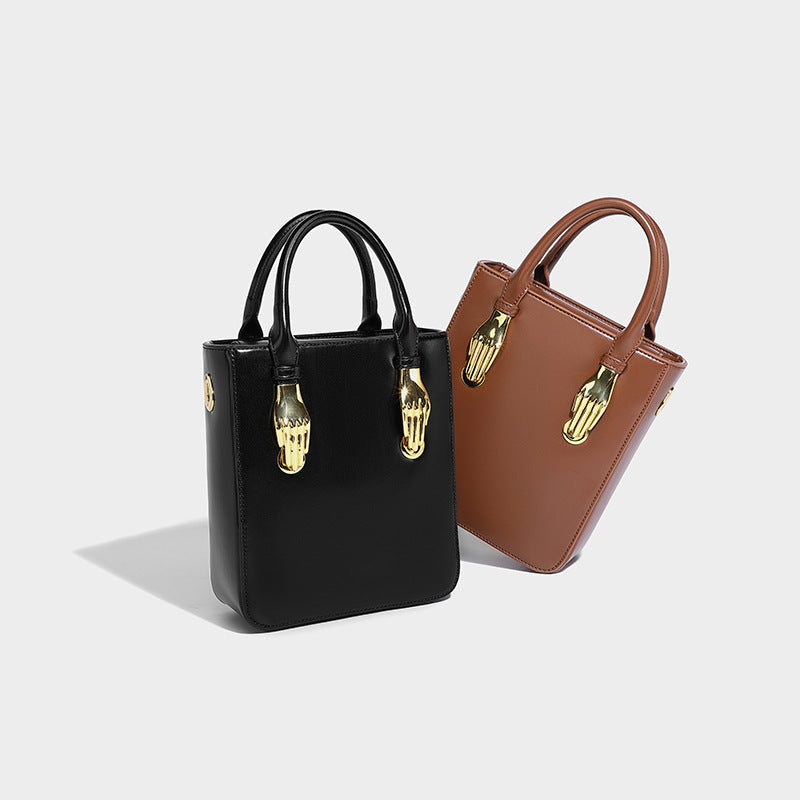 Small structured boxy top-handle bag with gold-tone hand-shaped hardware in black leather-look finish with detachable, detail