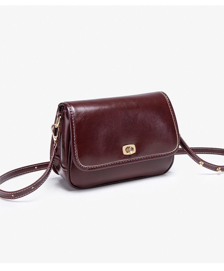 Kleine strukturierte Crossbody-Tasche mit Überschlag in glänzender Lederoptik, goldfarbenem Drehverschluss und verstellbarem Riemen