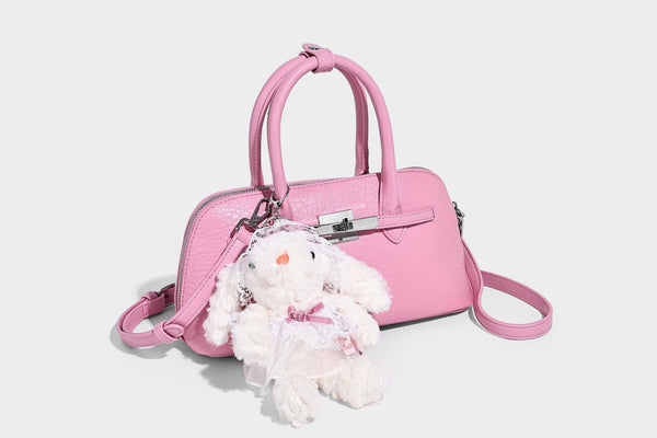 Small structured shell-silhouette top-handle bag with pebbled leather-look finish, silver-tone turn-lock hardware, and