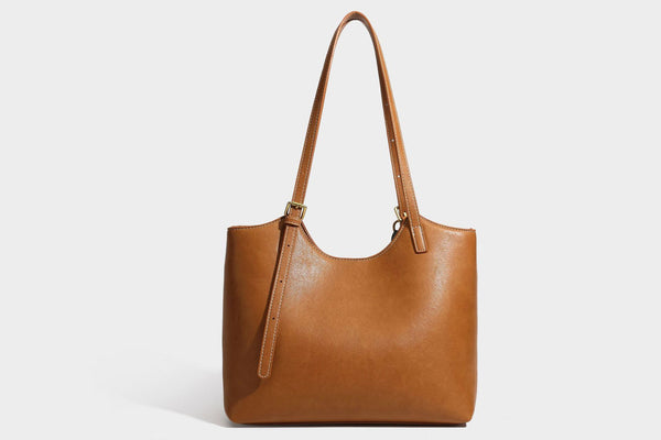 Structured smooth leather-look tote bag with long shoulder strap, gold-tone hardware, and hanging tassel-coin charm, detail