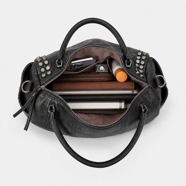 Black leather-look satchel bag with gunmetal rivet trim, grid-stitched paneling, dual rolled top handles, and curved zip