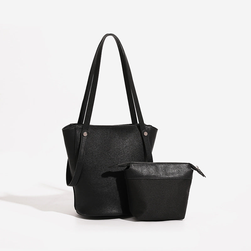 Strukturierte schwarze Bucket-Tote-Bag in Lederoptik mit schmalen Schulterriemen, Nietenbeschlägen in Silberoptik und sich verjüngendem Korpus, Detailansicht