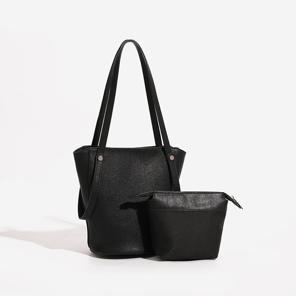 Structured black leather-look bucket tote bag with slim shoulder straps, silver-tone stud hardware, and tapered body, detail