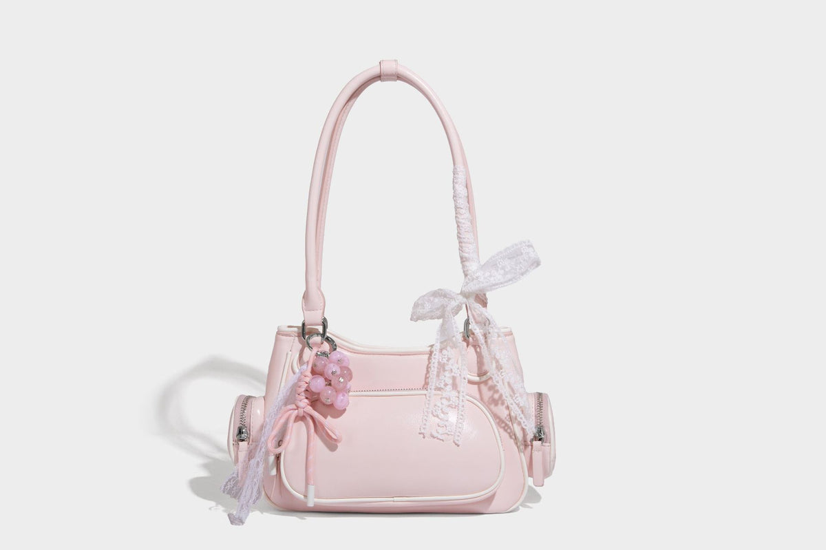 Kleine, formstabile Schultertasche mit glänzender Oberfläche, weißem Paspelbesatz, Spitzenschleife und rotem Perlenanhänger, Reißverschluss-Seitentaschen und silberfarbenem