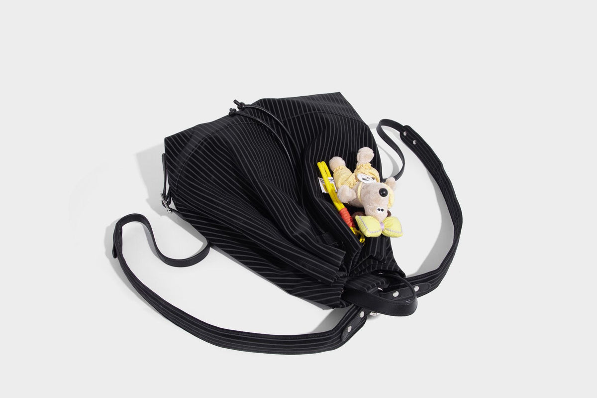 Schwarze wandelbare Rucksack-Handtasche mit Nadelstreifen, Kordelzugverschluss, Tragegriff aus Lederimitat und matten Metallbeschlägen, Detailansicht