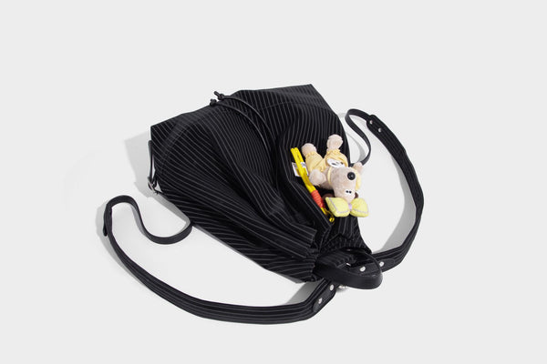 Schwarze wandelbare Rucksack-Handtasche mit Nadelstreifen, Kordelzugverschluss, Tragegriff aus Lederimitat und matten Metallbeschlägen, Detailansicht