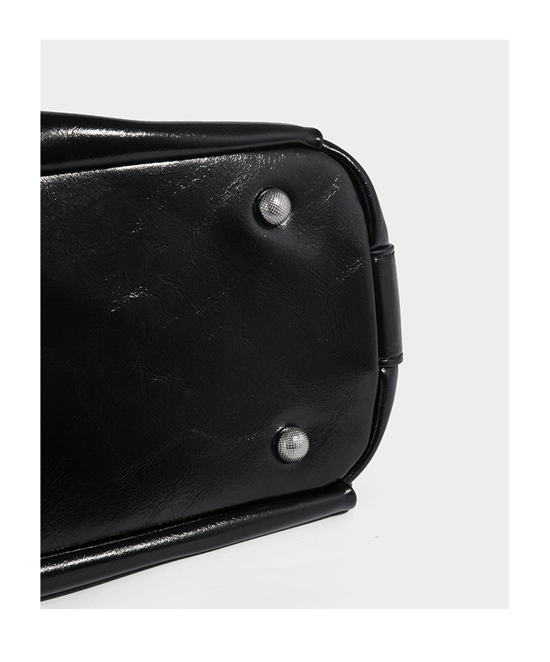 Glossy black slouchy hobo shoulder bag with zip closure, silver-tone ring hardware, and adjustable crossbody strap, detail