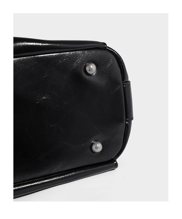 Glossy black slouchy hobo shoulder bag with zip closure, silver-tone ring hardware, and adjustable crossbody strap, detail