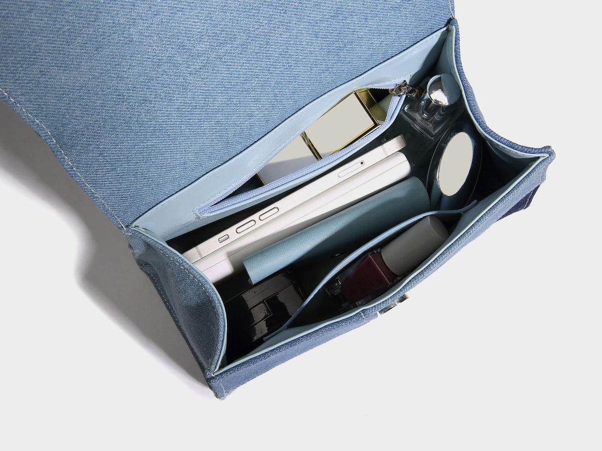 Structured patchwork denim trapezoid satchel bag with frayed panel trim, rounded top handle, and silver-tone hardware, detail
