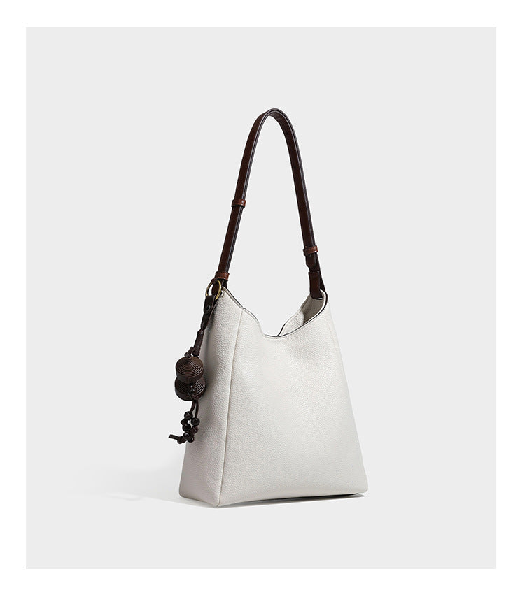 Hobo-Schultertasche in dunklem Espresso mit genarbter Oberfläche, warmen cognacfarbenen Details, verstellbarem schmalem Riemen, goldfarbenen Ringbeschlägen und geknotetem