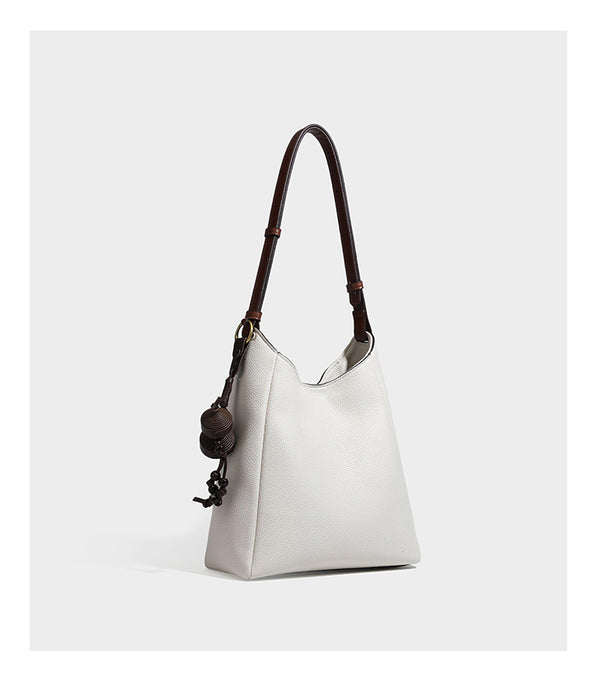 Hobo-Schultertasche in dunklem Espresso mit genarbter Oberfläche, warmen cognacfarbenen Details, verstellbarem schmalem Riemen, goldfarbenen Ringbeschlägen und geknotetem