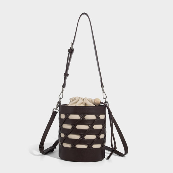 Small cylindrical woven lattice bucket bag with leather-look black trim, beige canvas body, wooden bead drawstring closure