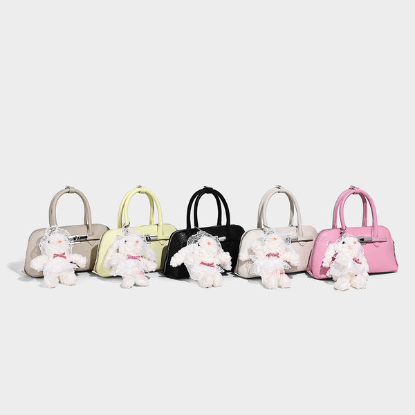 Small structured shell-silhouette top-handle bag with pebbled leather-look finish, silver-tone turn-lock hardware, and