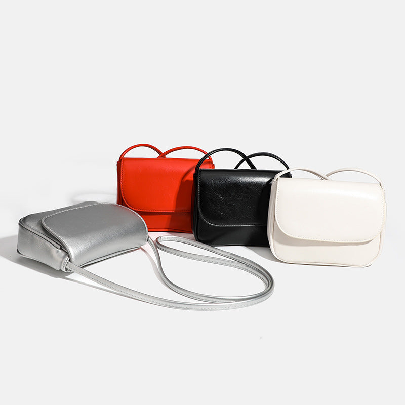 Compact rounded rectangular flap crossbody bag with glossy leather-look finish and long shoulder strap, detail view 2
