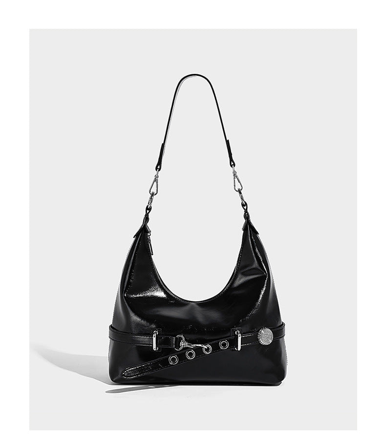 Glossy black slouchy hobo shoulder bag with silver-tone hardware, belt-style grommet strap at base, and long adjustable