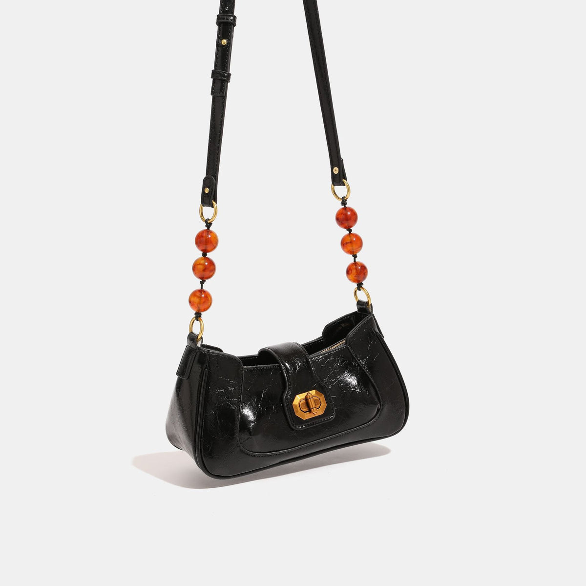 Compact glossy crinkled baguette shoulder bag with amber resin bead strap accent and gold-tone turn-lock closure, front view