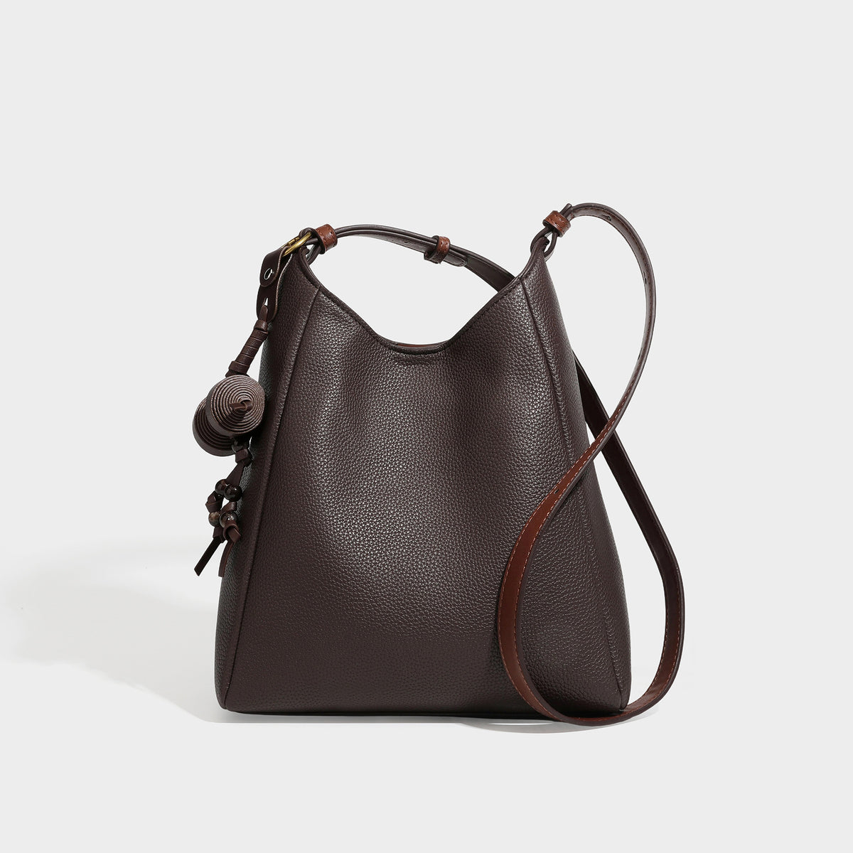 Dark espresso pebbled hobo shoulder bag with warm tan trim, adjustable slim strap, gold-tone ring hardware, and knotted