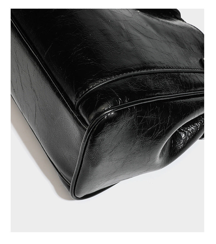 Structured glossy crinkled leather-look satchel with double top handles, front metal-plaque tab, silver-tone hardware, and