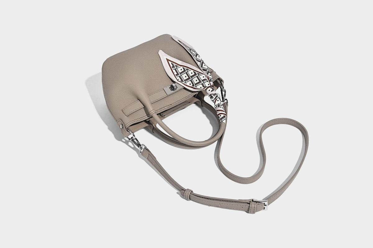 Kleine strukturierte Henkeltasche aus genarbtem Material in Taupe mit zwei Henkeln, bedrucktem Schalband, vorderem Drehverschluss und, Detail