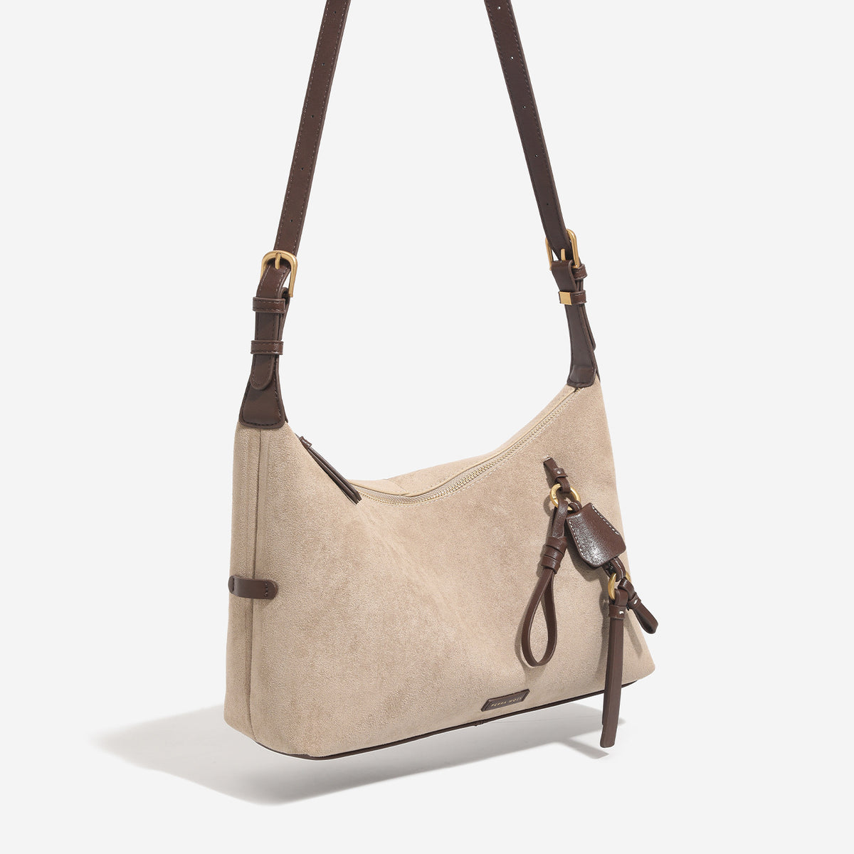 Sand beige slouchy hobo shoulder bag with dark brown trim, adjustable strap, gold-tone hardware, and decorative charm
