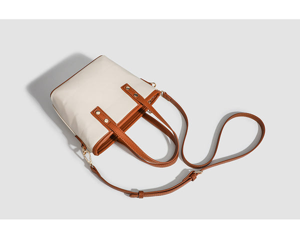 Kleine, formstabile Tote-Tasche mit Henkeln und Besatz in brauner Lederoptik auf einem cremefarbenen Korpus, Reißverschluss oben, goldfarbenen Nieten und