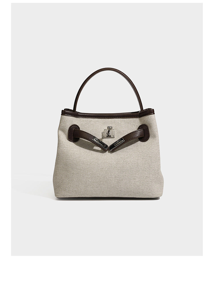 Small structured beige canvas top-handle bag with dark brown leather-look trim, silver turn-lock hardware, and detachable