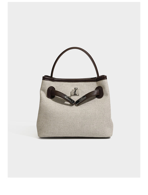 Small structured beige canvas top-handle bag with dark brown leather-look trim, silver turn-lock hardware, and detachable