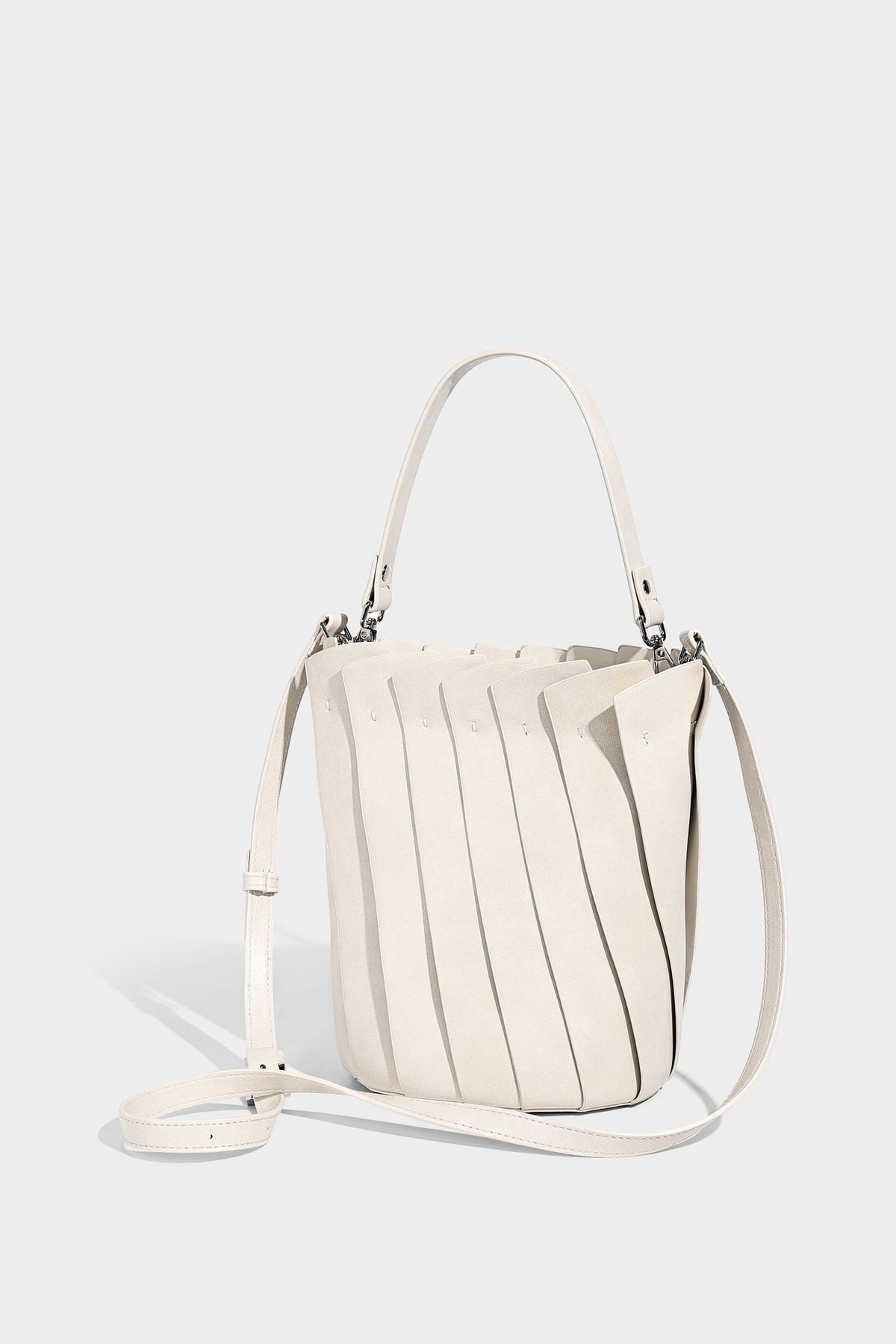 Structured pleated-panel bucket bag with curved top handle and detachable adjustable shoulder strap in smooth matte, detail