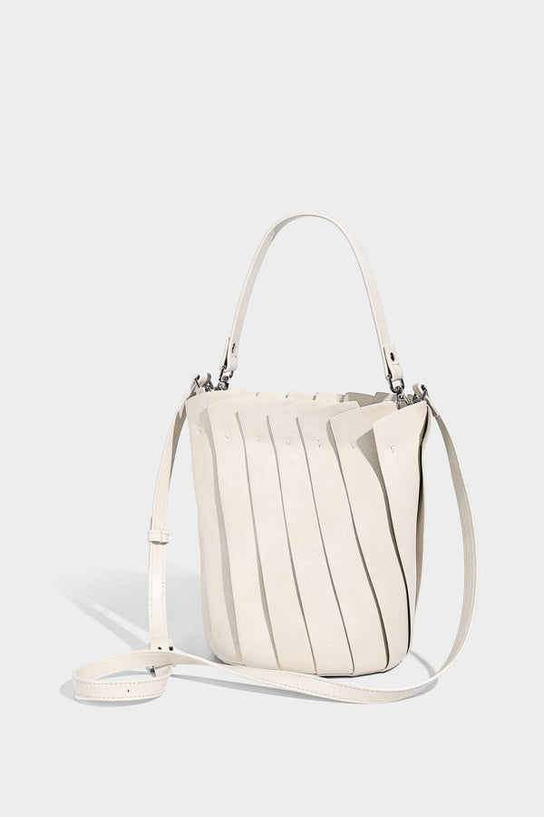 Structured pleated-panel bucket bag with curved top handle and detachable adjustable shoulder strap in smooth matte, detail