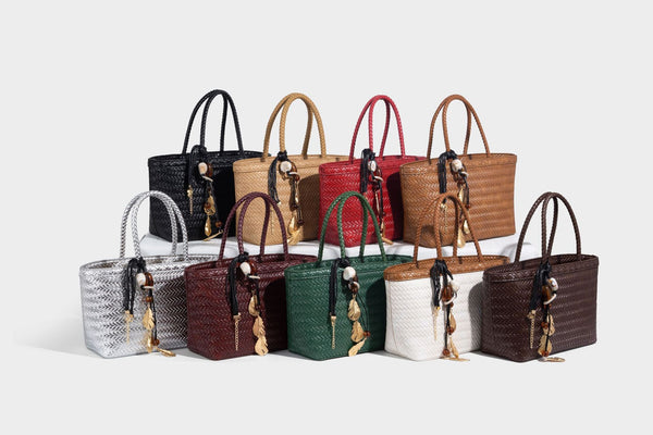 Structured chevron woven leather-look tote bag with braided top handles, gold feather charm, and adjustable shoulder strap