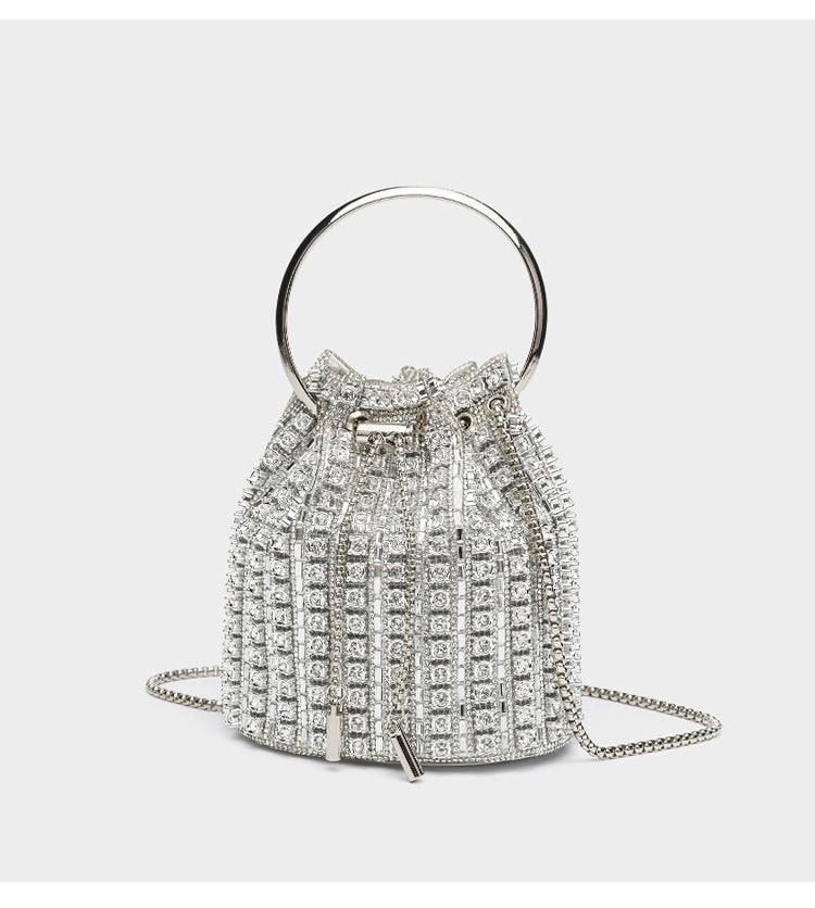 Mini crystal rhinestone bucket bag with circular ring top handle, drawstring closure, and silver chain shoulder strap, detail