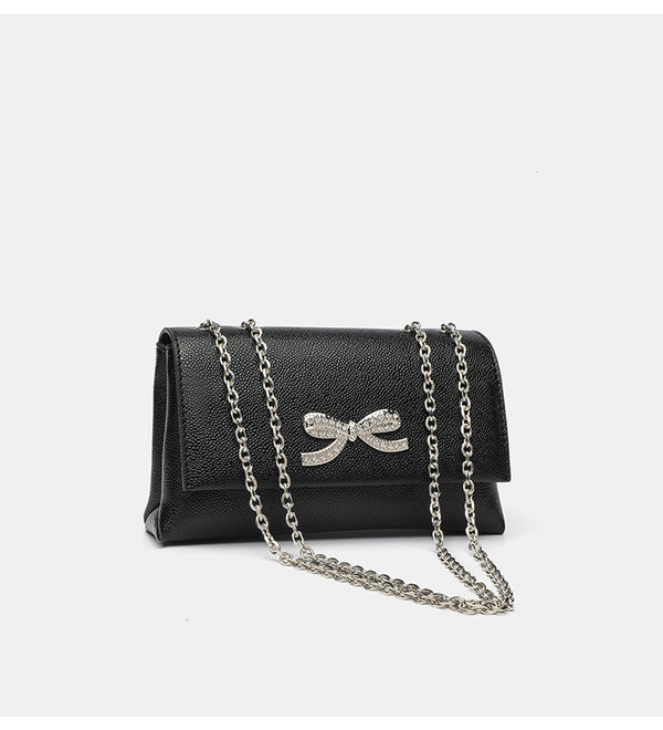 Structured rectangular flap crossbody bag with rhinestone bow and silver chain strap in pebbled finish, detail view 9