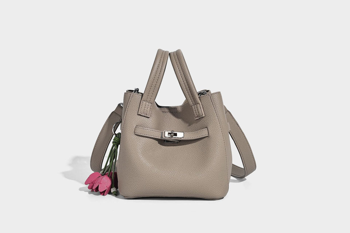 Small structured pebbled bucket tote bag with dual top handles, silver turn-lock front pocket, and detachable shoulder strap