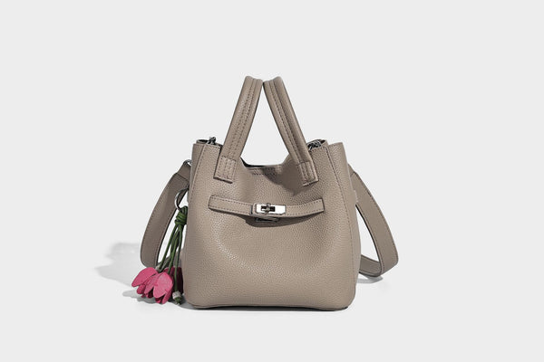 Small structured pebbled bucket tote bag with dual top handles, silver turn-lock front pocket, and detachable shoulder strap