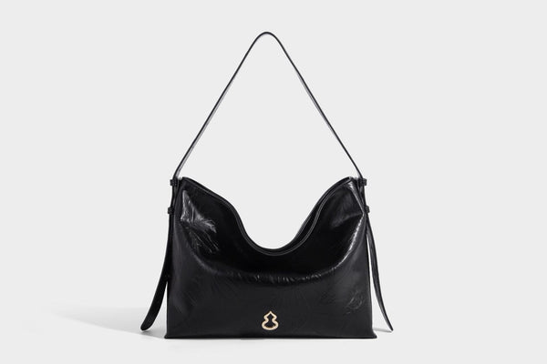 Large slouchy hobo shoulder bag in glossy crinkle leather-look finish with gold-tone emblem hardware and adjustable strap