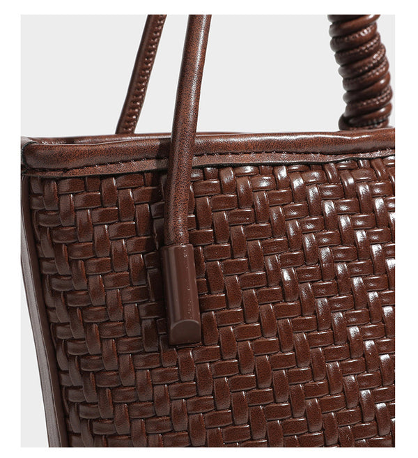 Structured woven-texture leather-look bucket bag in brown with knotted top handles, small front flap pouch, and adjustable
