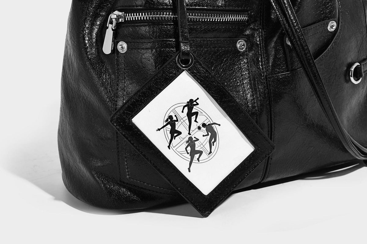 Glossy black convertible bucket backpack with silver grommet-studded straps, drawstring cinch closure, and front zip pocket