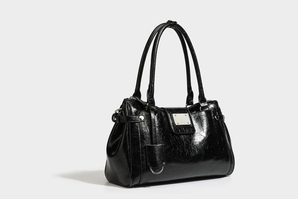 Structured glossy crinkled leather-look satchel with double top handles, front metal-plaque tab, silver-tone hardware, and