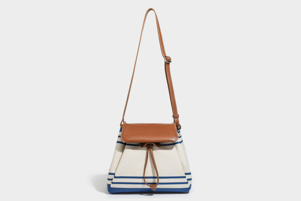 Cream canvas bucket bag with blue horizontal stripes, tan leather-look flap and trim, drawstring closure, silver-tone, detail