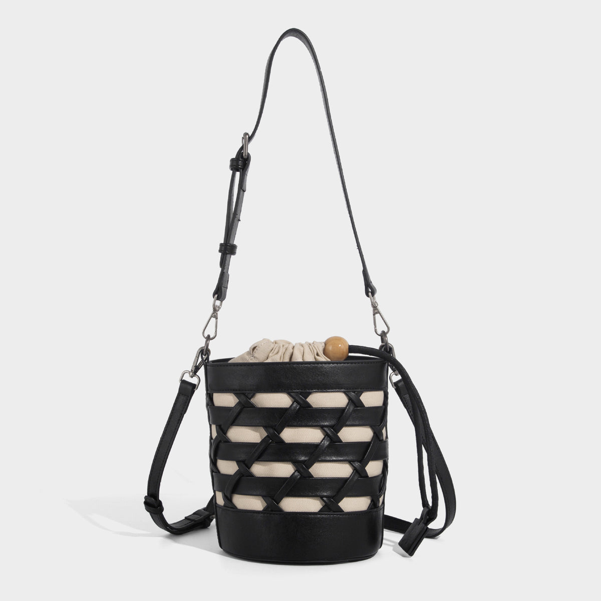 Small cylindrical woven lattice bucket bag with leather-look black trim, beige canvas body, wooden bead drawstring closure