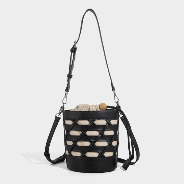 Small cylindrical woven lattice bucket bag with leather-look black trim, beige canvas body, wooden bead drawstring closure