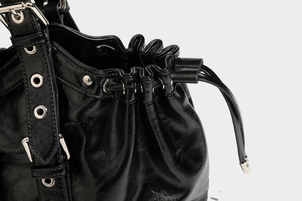 Large black glossy leather-look tote bag with silver buckle straps, eyelet grommet panels, drawstring side gathers, and