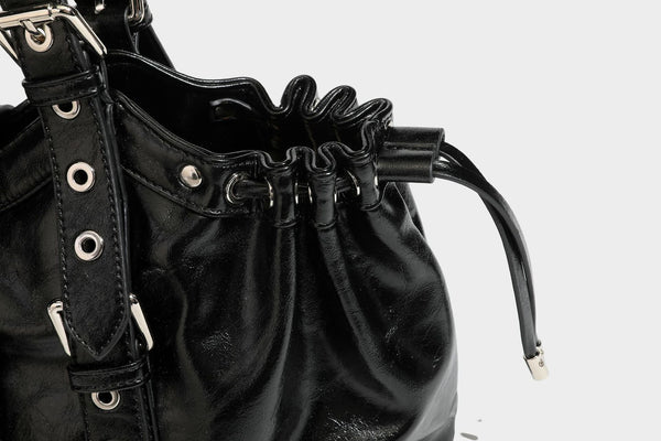 Large black glossy leather-look tote bag with silver buckle straps, eyelet grommet panels, drawstring side gathers, and