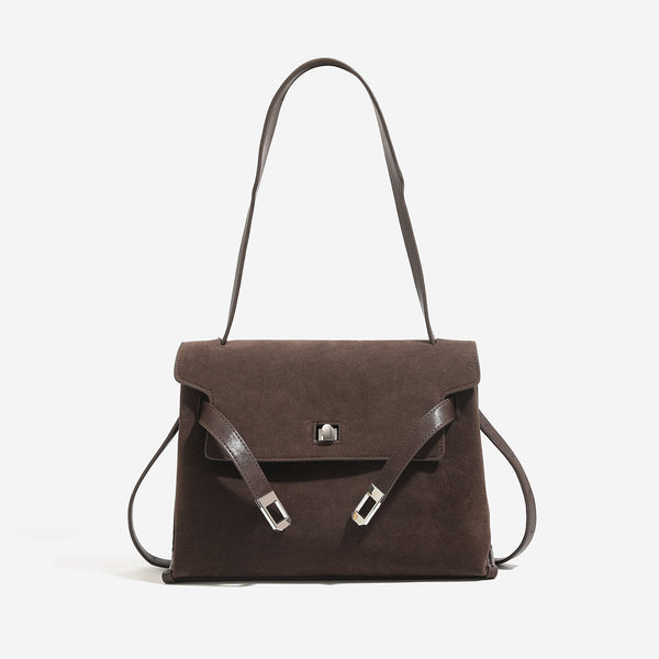 Structured trapezoidal flap satchel bag with silver-tone turn-lock clasp, decorative front strap tabs, gusseted sides, and