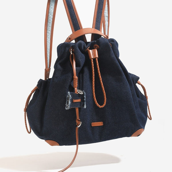 Weicher Rucksack in Beutelform mit Kordelzug und geflochtenem Kordelverschluss, Besätzen in hellbrauner Lederoptik und Eckenschutz, Vorderansicht